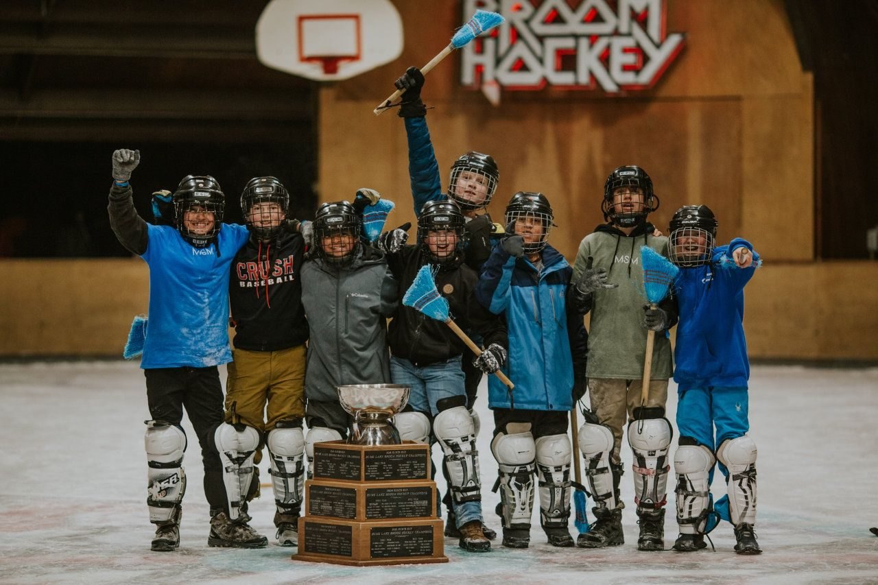 A winter camp broom hockey team posed together on the Ark’s ice in matching jerseys after their game.