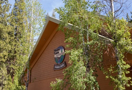 The steep-gabled Ponderosa Chapel, its dark red siding and A-frame roof rising among pines and aspens.