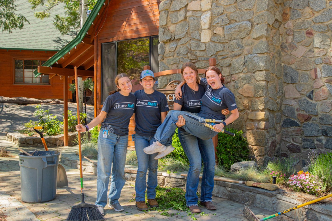 Summer staff with brooms and buckets outside a stone building at Hume SoCal.