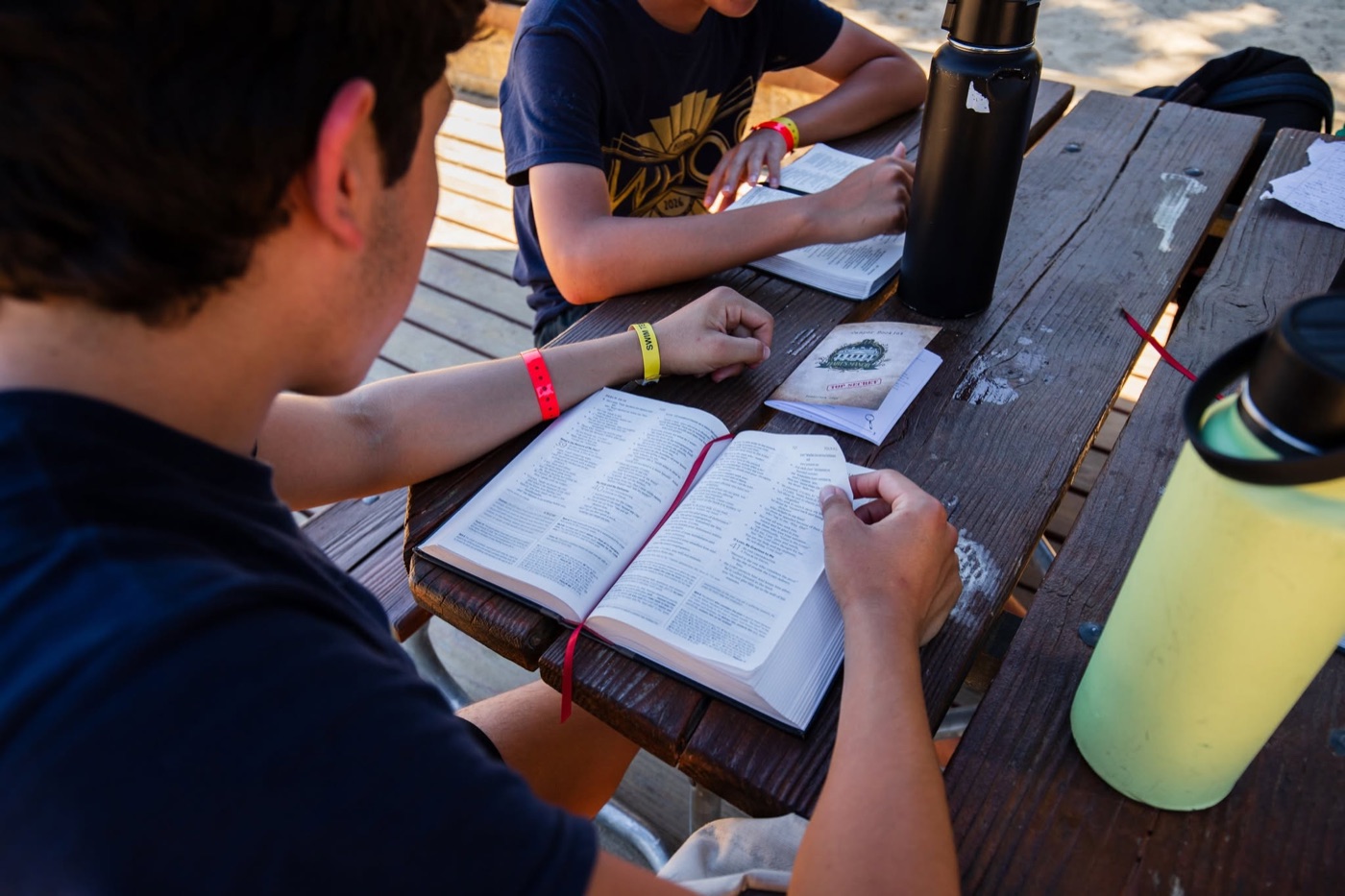 A student reading a Bible at a picnic table.
