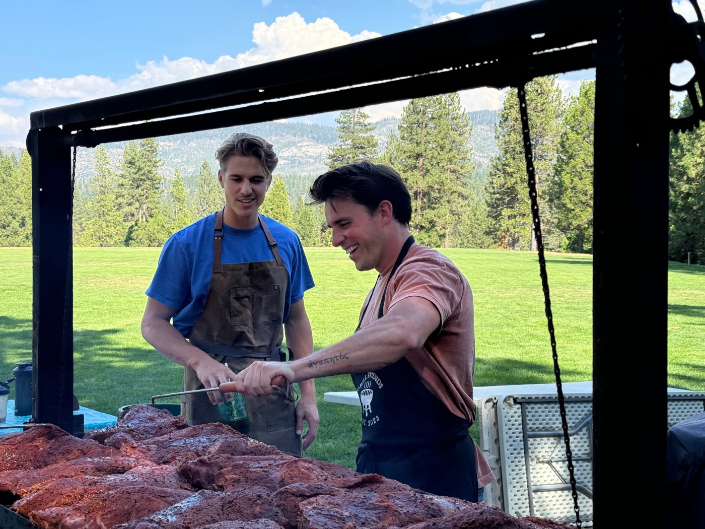 Staff grilling at an outdoor dinner with the meadow behind them.