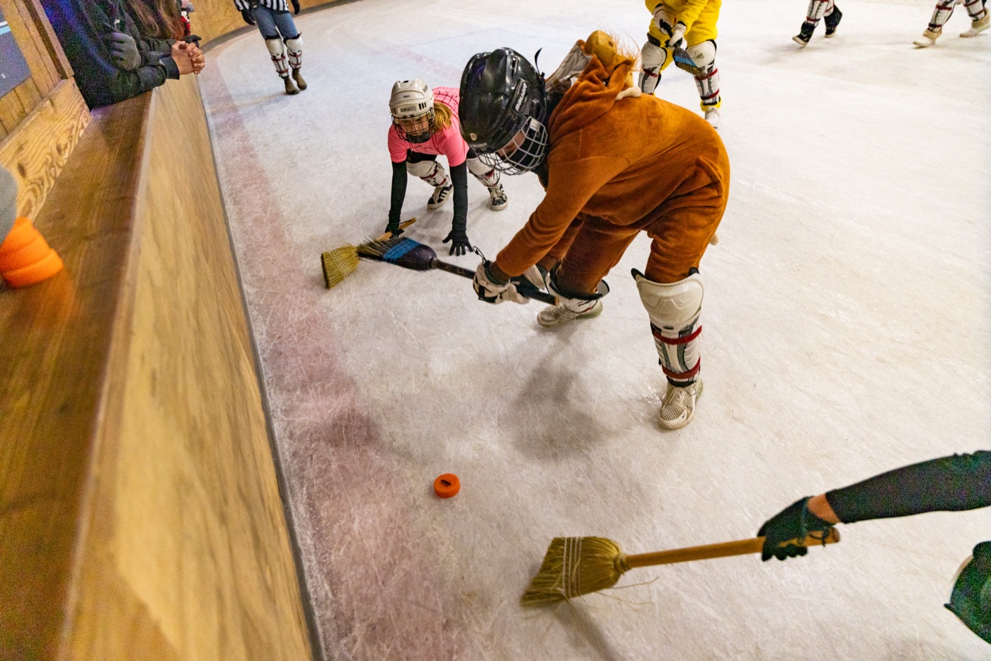 Campers playing broom hockey on the rink at winter camp.