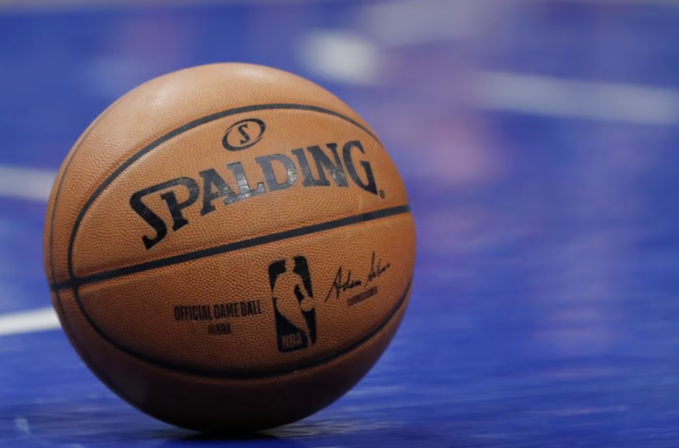 A Spalding basketball resting on a blue court.