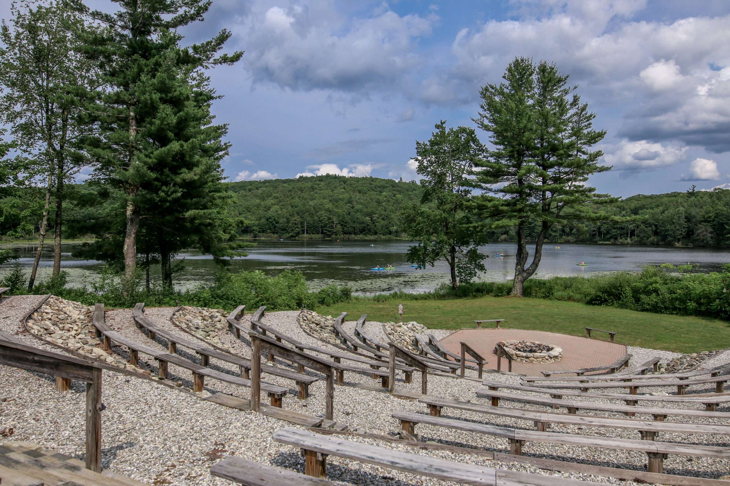 A serene summer view of the Hume New England Amphitheater/Victory Circle overlooking Steadman pond during the daytime.